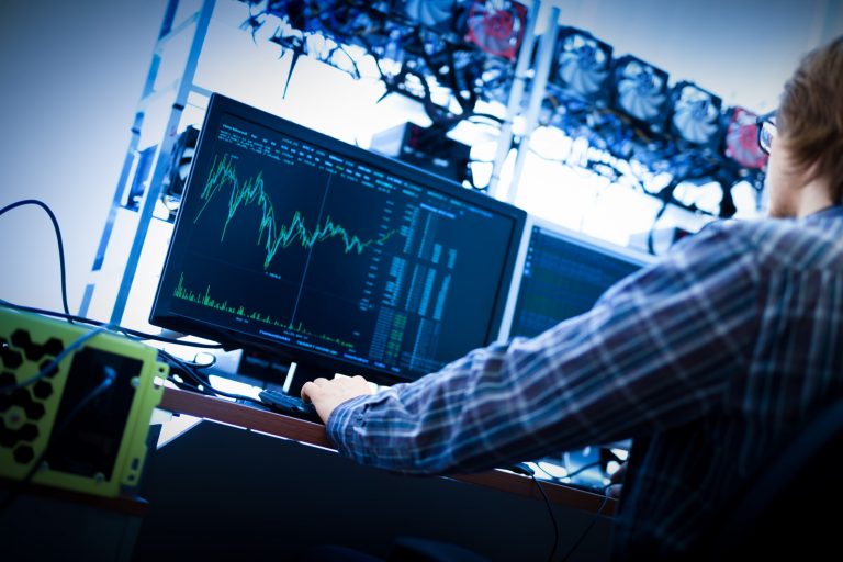 Man working on the computer with bitcoin analyst software.